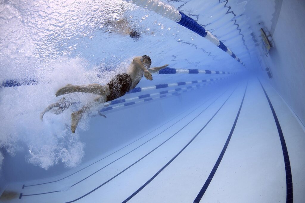 afvallen met zwemmen kan het beste als je fanatiek zwemt. deze man doet een borstcrawl in een wedstrijdbad
