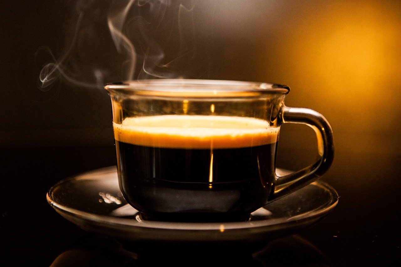 Koffie in een galzen kopje, staat te dampen op een glazen schoteltje