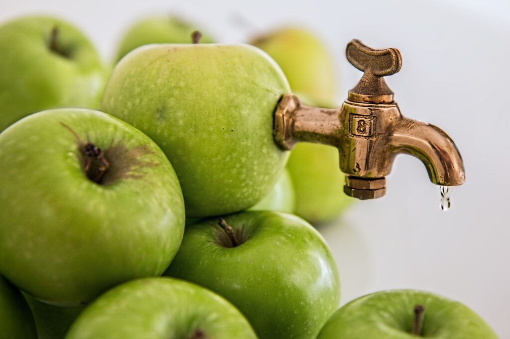 alcohol vervanger appelsap komt via een kraan uit een stapel groene appels.
