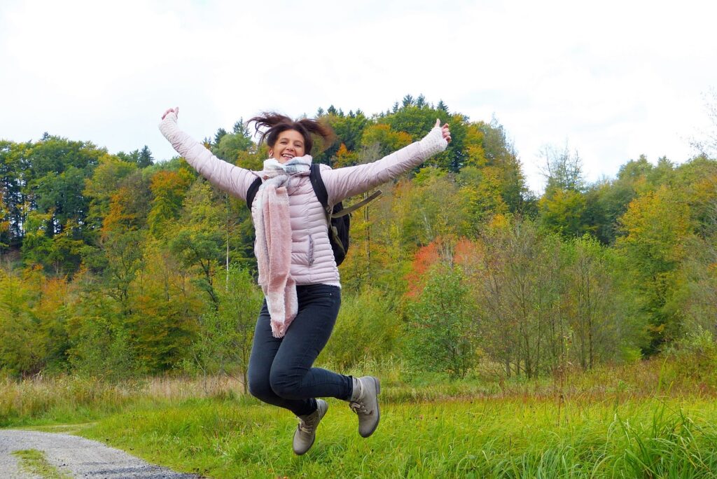 vrouw in een zalmrose jas springt een gat in de lucht