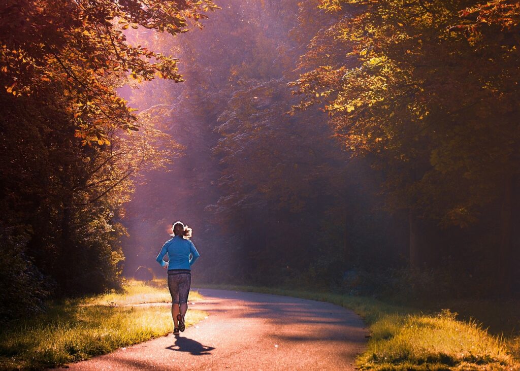 afvallen met hardlopen. vrouw in het bos met de opkomende zon.