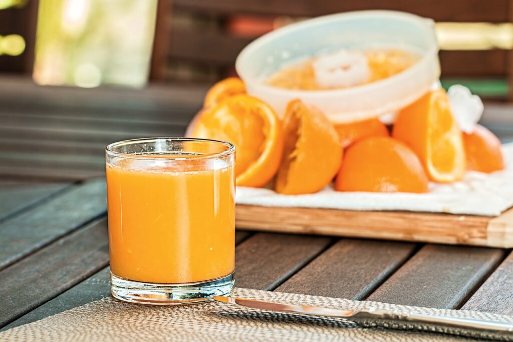 een glas ver geperste sinaasapplesap voor een plank met sinaasappels